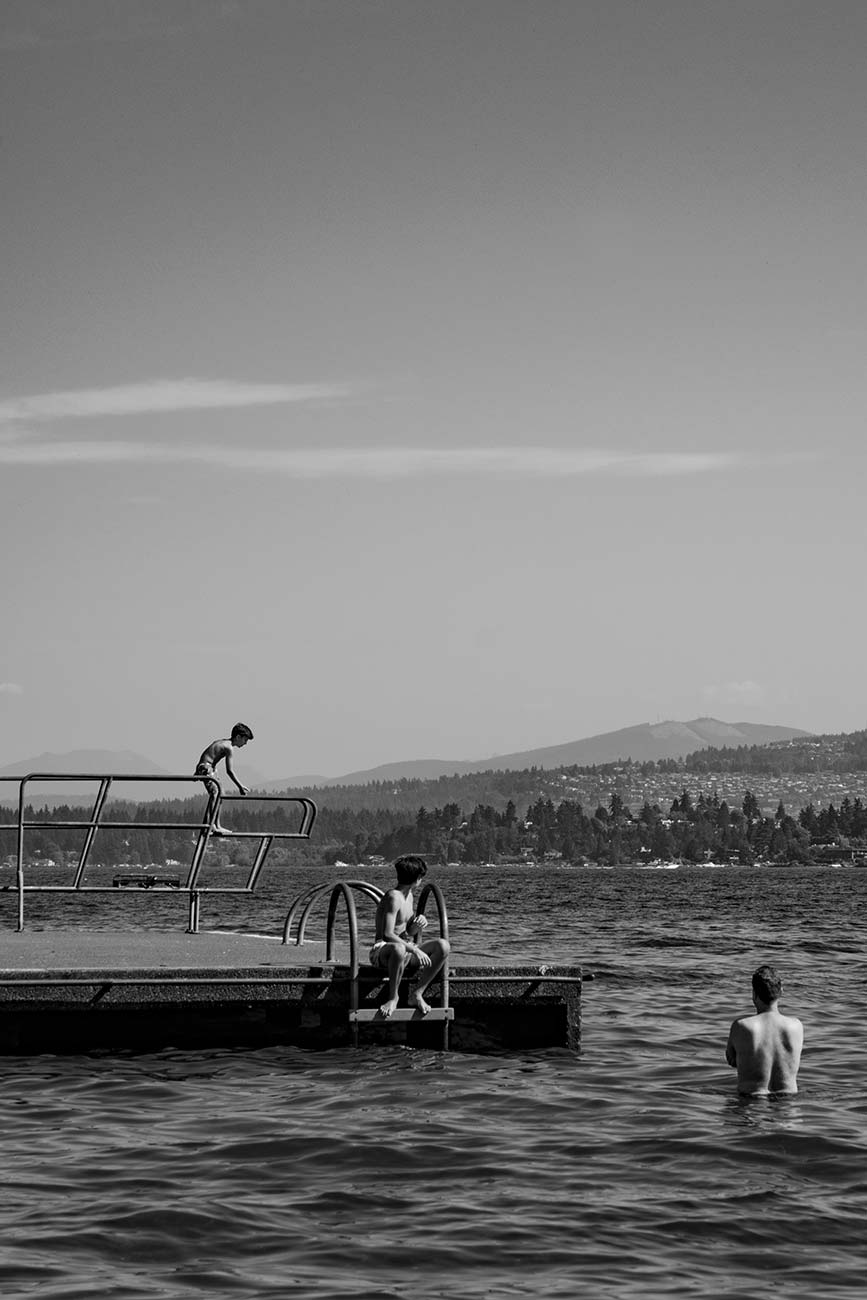 Black and white, three boys playing on floating platform in the water at Lake Wahington