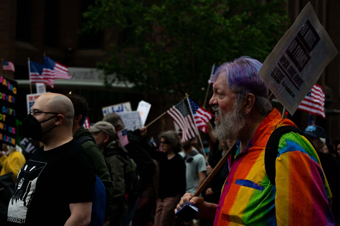 Old man with purple hair and a rainbow shirt joins in the No Kings Day Protest